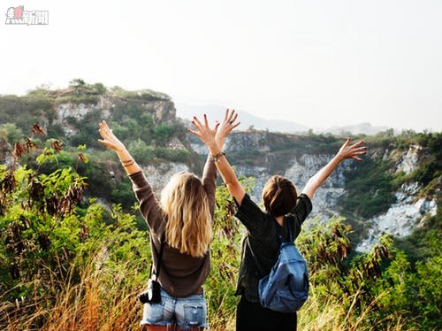 Two Girls on Two of a Mountain With Their Hands in the Air during Day